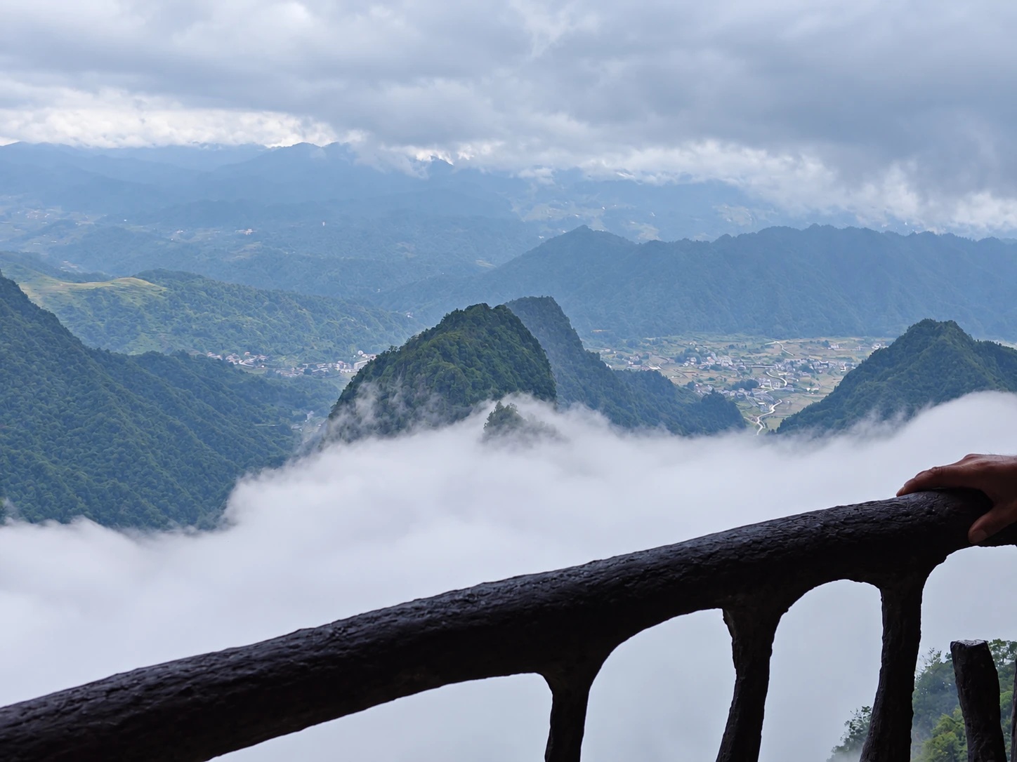 从山顶栏杆旁俯瞰云海与远山