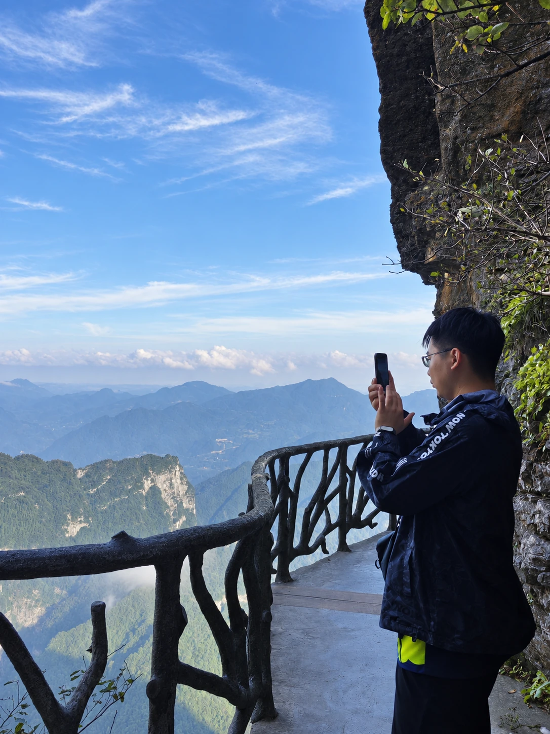 在悬崖栈道上拍摄远山的游客