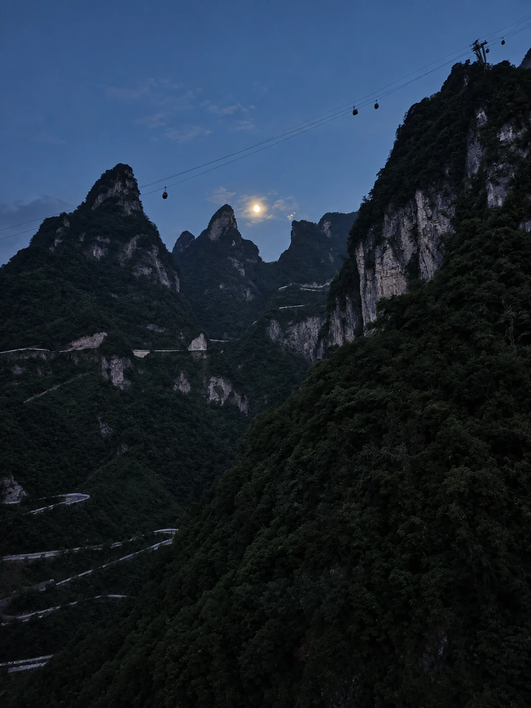 月色下掠过群峰的索道轿厢